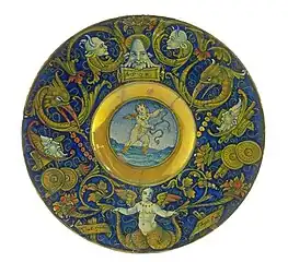 Plat peint et doré, avec un cupidon dans le cavet et des grotesques, sur fond turquoise, sur le large bord, Maître Giorgio Andreoli, Gubbio, vers 1525.