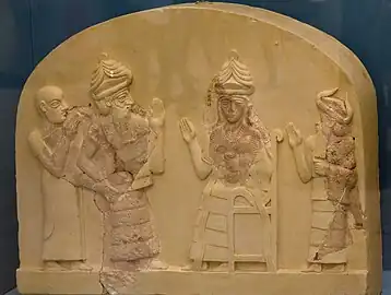 Reconstituion d'une plaque en calcaire où l'on peut voir trois personnages debout autour d'un personnage absent qui semble assis sur un trône.