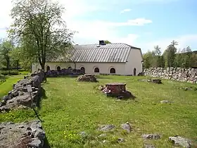 Autel au milieu de ruines, devant un bâtiment conservé.