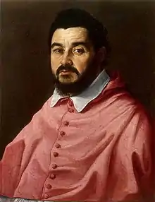 Peinture du buste d'un cardinal brun et barbu en tenue pourpre et au col blanc, qui regarde directement le spectateur.
