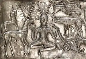 Gravure sur métal montrant un homme assis avec des cornes sur la tête, entouré d'animaux, dont un cerf.