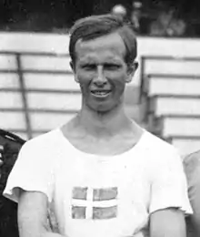 Photographie montrant le haut du corps de Gustaf Dyrssen, portant un t-shirt blanc sur lequel se trouve un drapeau suédois.