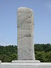 pierre taillée présentant 4 faces gravées, se dressant en pleine nature.