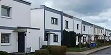 Photographie en couleur d’une enfilade de maisons mitoyennes sur deux niveaux.