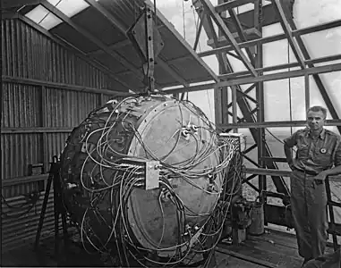 Photographie d'une sphère couverte de câbles dans un abri en tôle rudimentaire.