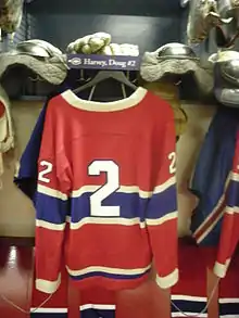 Photographie du maillot rouge des Canadiens accroché dans le vestiaire avec le numéro 2 écrit dessus