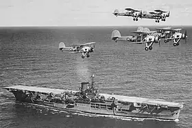 Photographie de sept biplans survolant un porte-avions
