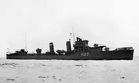 Photo en noir et blanc d'un destroyer vu depuis tribord. Des hommes sont debout en rang sur le gaillard d'avant.