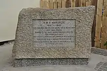 Photographie d'un texte gravé dans un bloc de granit, servant de mémorial.