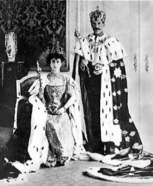 Photographie en noir et blanc d'un roi et d'une reine portant leurs insignes royaux.