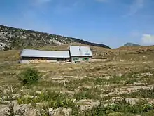 Bergerie isolée dans un terrain de montagne mi-rocheux mi-herbeux.