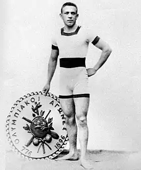 Portrait de l'athlète hongrois Alfréd Hajós debout à côté d'un disque représentant les jeux olympiques.