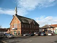 Vue de trois quarts de la mairie d'Easingwold avec sa brique rouge à arches jaunes et ses toits pentus de tuile grise, par beau temps.