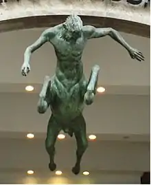 Statue représentant un homme-cheval : tête et buste d'homme, corps, membres et queue de cheval, vu de dessous.