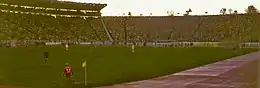 Vue panoramique de l’intérieur d’un stade de football, dans lequel un match se dispute devant des tribunes pleines.