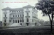 Photo ancienne représentant un bâtiment à deux étages, de style occidental, situé dans un parc.
