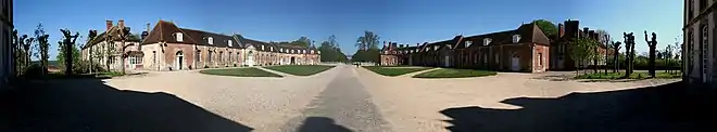 Vue panoramique de deux rangées de bâtiments, une grille dans le fond.