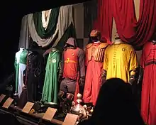 Plusieurs tenues sportives vertes, rouges ou jaunes. Certaines comportent des protections en cuir au niveau de la poitrine ou des genoux.