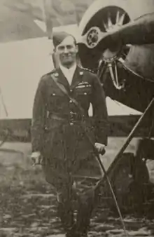 Photographie noir et blanc d'un homme en uniforme devant un avion.