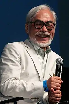 Homme asiatique avec des cheveux blancs, une barbe blanche et des lunettes noirs.