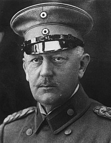 Photo du général en buste et en uniforme, moustache tombante et casquette visée sur le crâne.