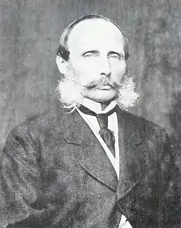 photographie noir et blanc : portrait d'homme chauve, moustachu avec des favoris très fournis