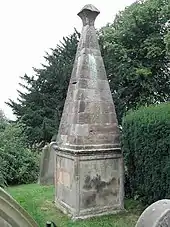 Photo d'un monument en pierre grise composé d'un socle cubique sur lequel se dresse une pyramide aux pentes abruptes coiffée d'un cabochon