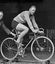 Un homme sur un vélo posé sur un système à roulettes.