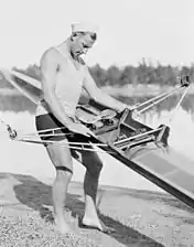 Un homme portant à deux mains un rameur.