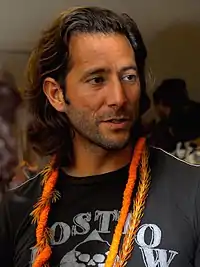 acteur en T-shirt noire avec fine écharpe ou ruban orange autour du cou