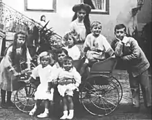 Photographie en noir et blanc montrant un groupe d'enfants dans et autour d'une charrette.