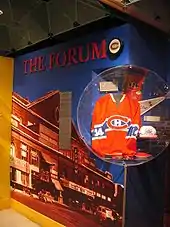 Photo d'un pan de mur consacré au Forum de Montréal : photo couleur du forum, sur monté du titre The Forum et d'un palet avec le logo des Canadiens de Montréal ; dans un angle un maillot numéro 14 des Canadiens de Montréal.