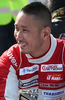 Photo d'un homme souriant, en combinaison de course rouge et blanche