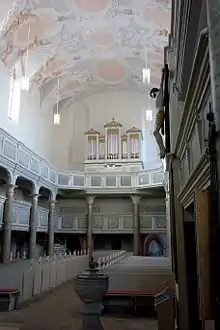 Photographie couleur d'une nef d'église, vue vers la façade et l'orgue, comportant deux tribunes qui courent des deux côtés.