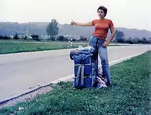 femme tendant le pouce dans l'herbe au bord d'une route