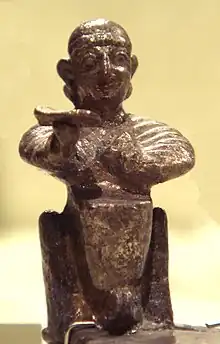 Photo d'une statuette en terre représentant un homme souriant assis