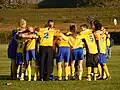 Jeunes joueurs amateurs de football discutant dans un huddle.