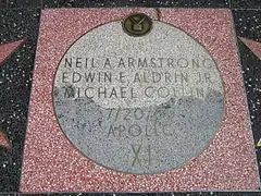 Photographie en couleur d'un pavage commémoratif mentionnant les noms des astronautes d'Apollo 11.