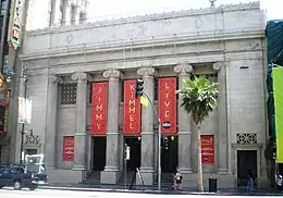 Façade à colonnades avec des 3 drapeaux rouges tendus entre les colonnes avec l'inscription Jimmy Kimmel Live en lettres dorées.