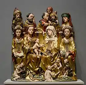 Sculpture polychrome représentant sainte Anne, la Vierge et Jésus, assis sur des trônes et encadrés par plusieurs personnages eux-mêmes assis ou debout.