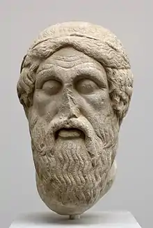 Tête d'une statue en marbre représentant un homme barbu.