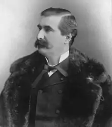 Photographie noir et blanc d'un homme en habit avec un manteau de fourrure.