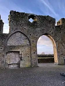 Photographie des arches gothiques d'une église en ruines, dont l'une a été murée.