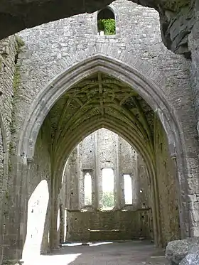 Photographie couleur d'un intérieur d'église partiellement ruiné, dont certaines voûtes manquent