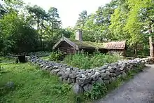 Un vieux bâtiment en bois entouré d'un muret en pierre.