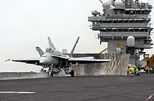 Chasseur F/A-18 sur le pont d'envol, prêt au catapultage.