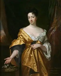 portrait d'une femme élégante en somptueuse robe dorée, bras droit appuyé sur un guéridon