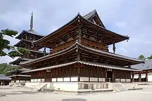 Un grand bâtiment en bois avec un toit en croupe et à pignon principal et un toit secondaire donnant l'impression d'un bâtiment à deux étages. Entre ces toits il y a une véranda ouverte grillée entourant le bâtiment. Sous le toit secondaire, il y a un toit joint recourbé. Derrière le bâtiment il y a une pagode à quatre étages en bois avec toit entourant recourbé sous le premier toit.