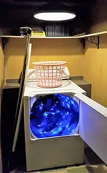 Une machine à laver dont la porte ouverte laisse entrevoir un tunnel éclairé de bleu