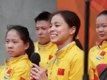 Photo de Huang Shanshan en tenue de l'équipe de Chine tenant un micro à deux mains